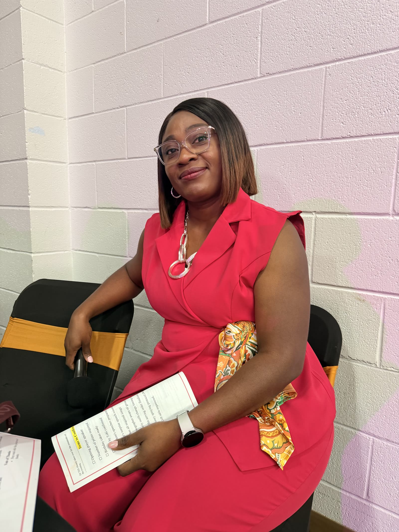 Bhee seated with her run-of-show notes in a red outfit